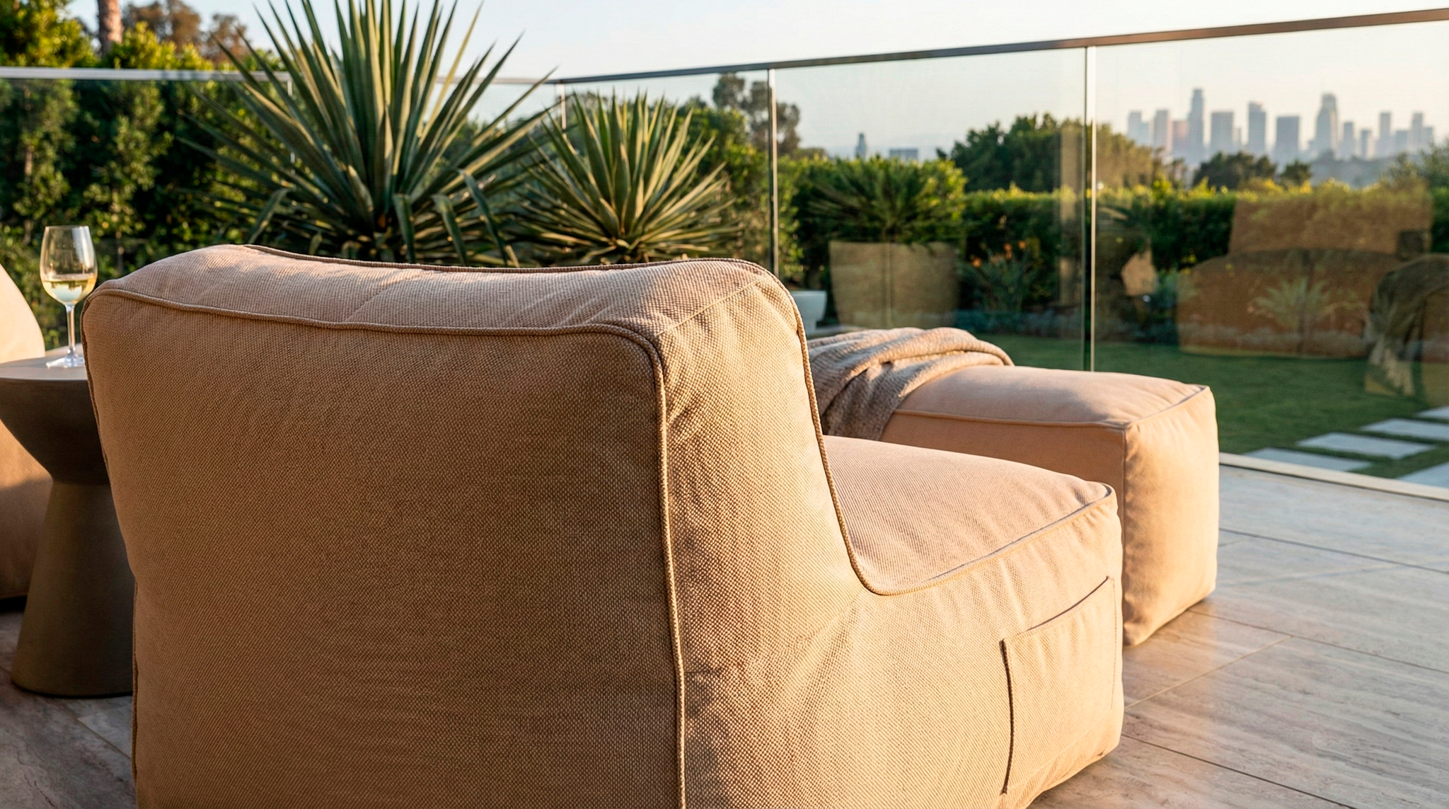 Beige outdoor sofa on a wooden deck with a cityscape view in the background