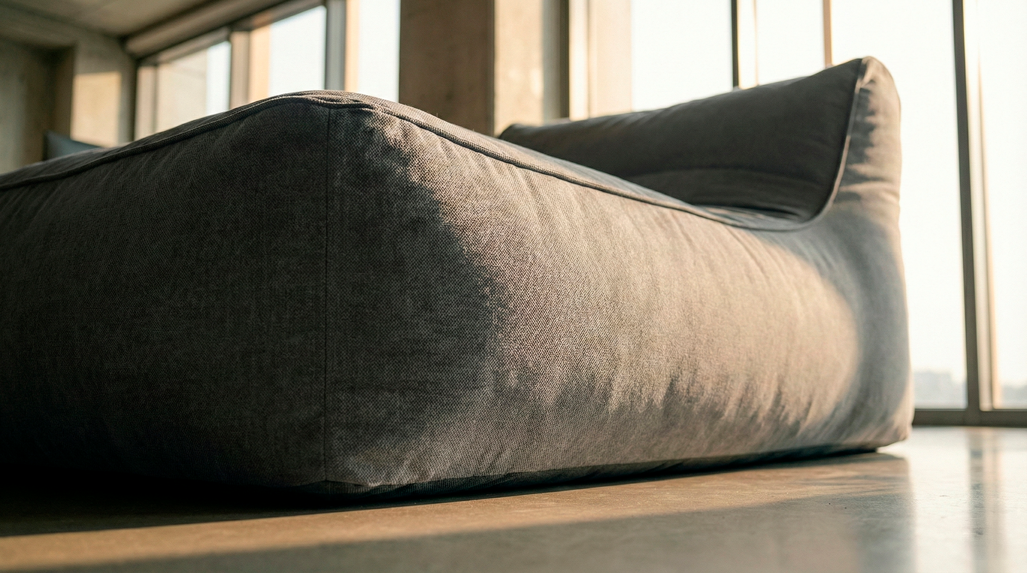 Modern, curved gray sofa in a room with large windows